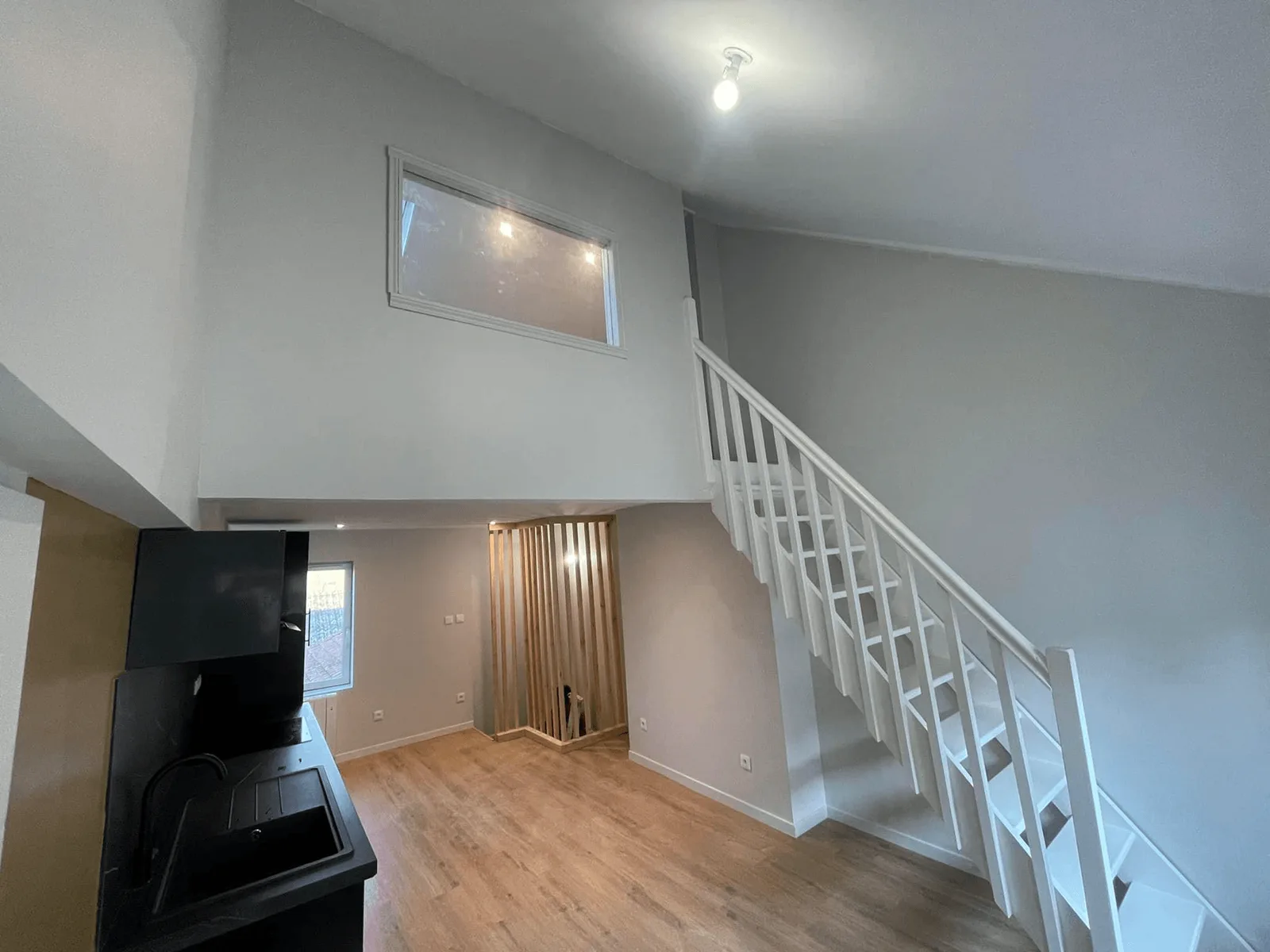 Intérieur avec mezzanine, escalier blanc et murs clairs